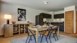 Een moderne keuken met donkere kastjes, een houten eettafel en vier stoelen.