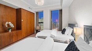 A hotel room with two beds, a wooden wardrobe, a modern chandelier, and a city view. - FIRST CLASS | 3BR | Burj Khalifa & Fountain view (Downtown)