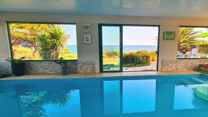Un espace piscine avec vue sur l’océan, un coin salon abrité et un escalier menant à l’extérieur.