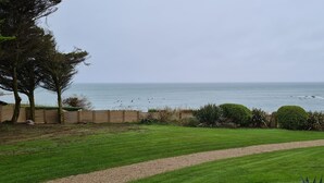 Une vue sur la côte, avec une pelouse verdoyante, une clôture en bois et un rivage rocheux.