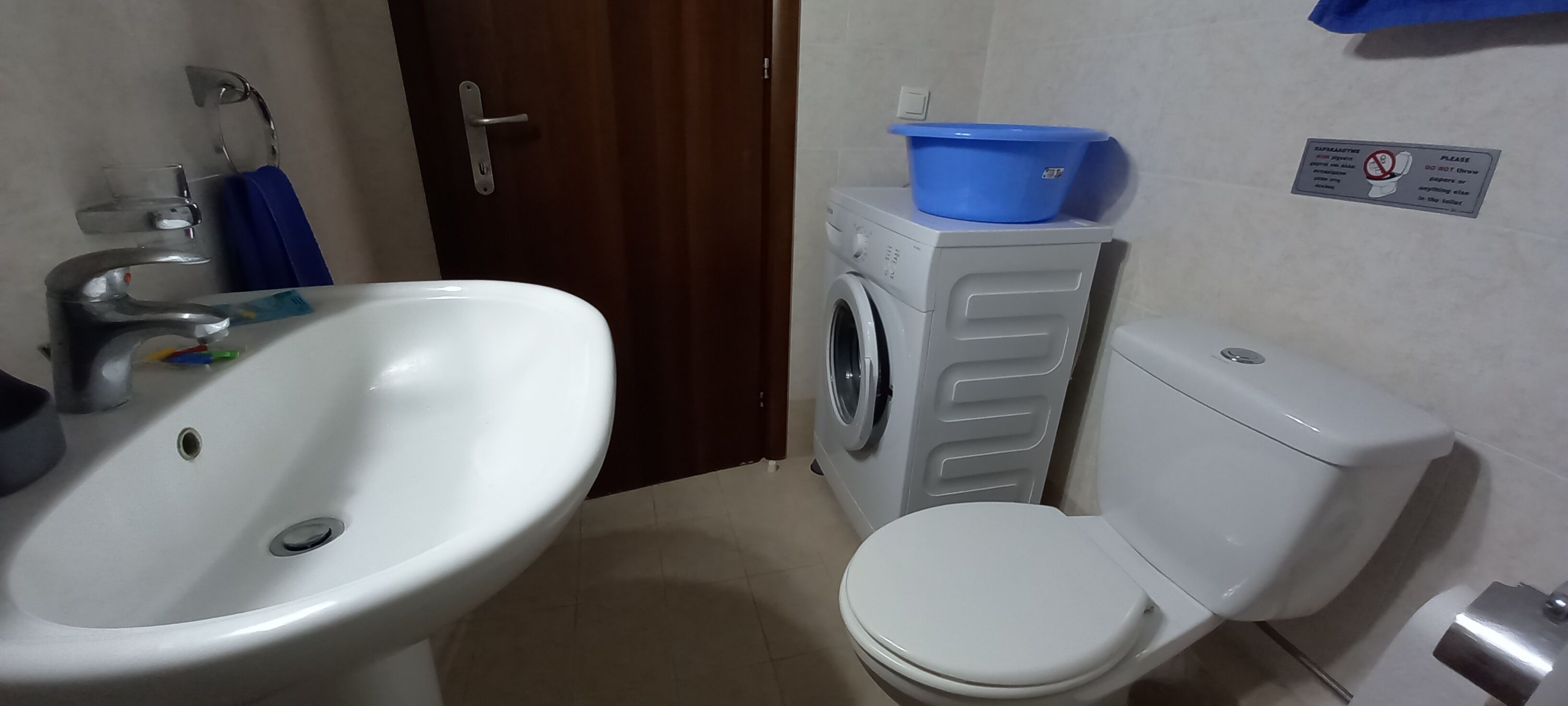 Une salle de bain avec un lavabo, un lave-linge et des toilettes.