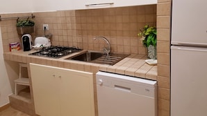 Een praktische keuken met een gasfornuis, spoelbak en vaatwasser.