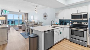 Eine moderne Küche mit Geschirrspüler, Backofen und Mikrowelle, ein Essbereich mit Blick und ein Balkon mit Aussicht.