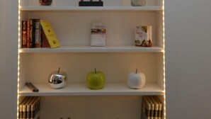 Een boekenplank met verschillende objecten, waaronder boeken, een fles en decoratieve items.