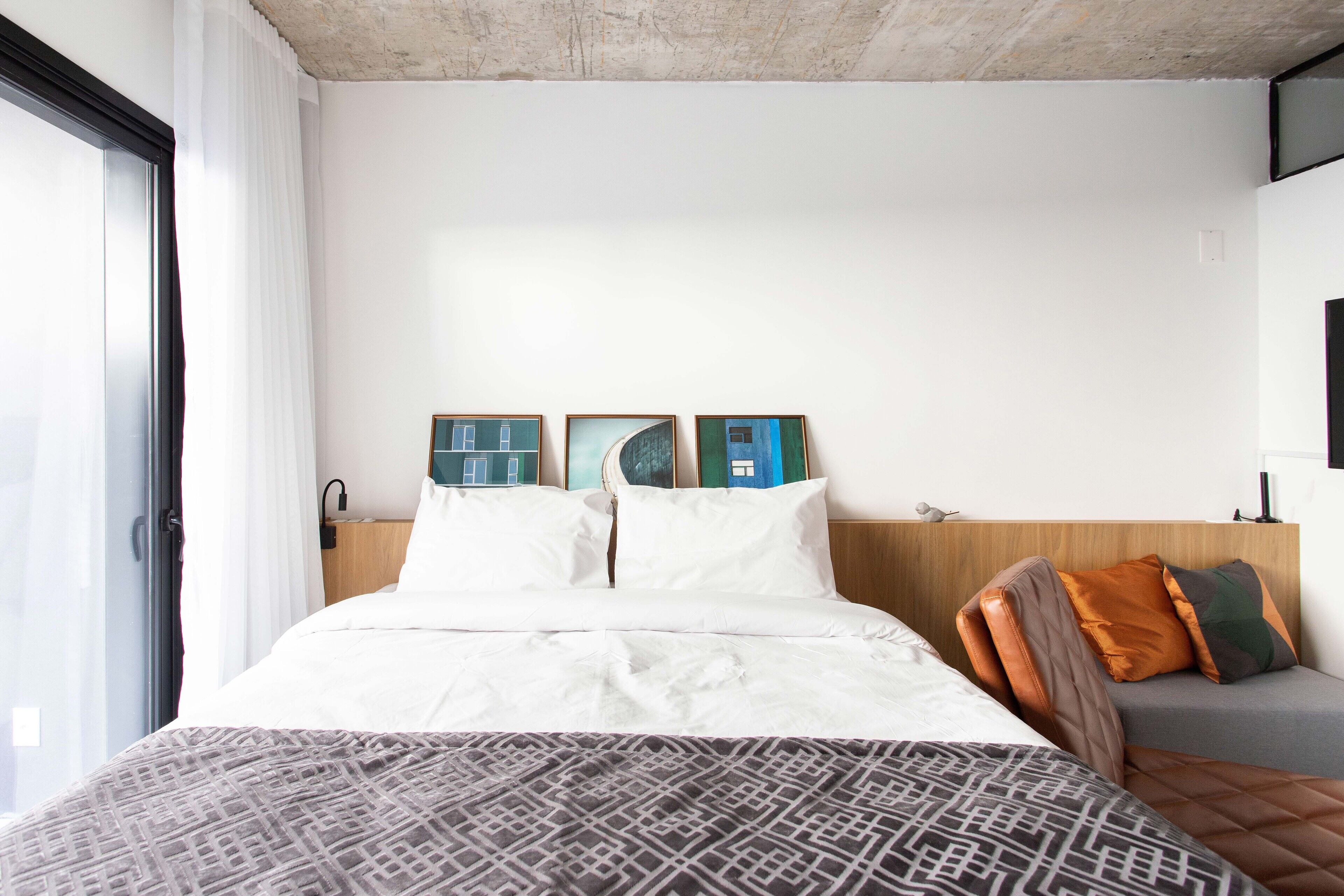 A hotel room with a large bed, a small sofa, and three framed pictures on the wall.