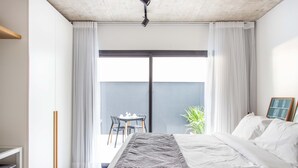 Ein modernes Hotelzimmer mit einem großen Bett, einem Schreibtisch und einem Balkon mit Tisch und Stühlen.