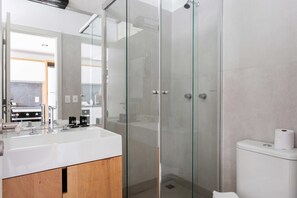 Ein modernes Badezimmer mit einer Duschkabine, einem weißen Waschbecken und einer Toilette.