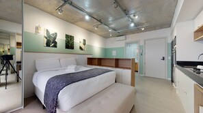 Ein modernes Hotelzimmer mit einem großen Bett, einem Schreibtisch und einer Küchenzeile.