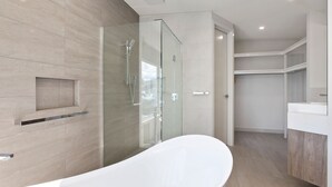 Ein modernes Badezimmer mit einer freistehenden Badewanne, einer Duschkabine aus Glas und einem eingebauten Waschtisch.