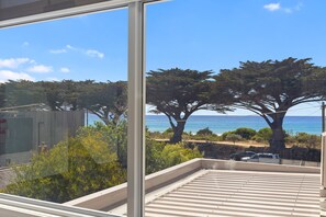 A view from a balcony overlooking a coastal area with trees and the sea.