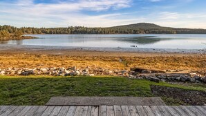 A lakeside view with a wooden deck, calm water, and forested hills in the background. - Waterfront Home! Newly Remodeled! (weow) (Friday harbor)