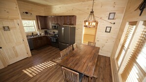 A wooden cabin interior with a kitchen, dining table, and chairs. - Quiet Family Cabin on Private Mountain Top-Awesome Location! (Sevierville)