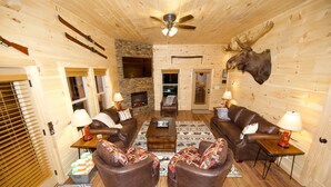 A log cabin interior with a fireplace, leather furniture, and a mounted moose head. - Quiet Family Cabin on Private Mountain Top-Awesome Location! (Sevierville)