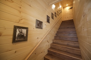Staircase with handrail leads to an upper level, adorned with framed photographs.