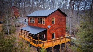A two-story wooden cabin with a deck, surrounded by trees. - Quiet Family Cabin on Private Mountain Top-Awesome Location! (Sevierville)