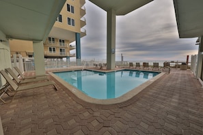 A rooftop pool with hexagonal tiles, lounge chairs, and a view of the city skyline.