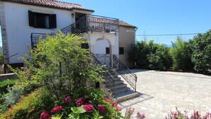A two-story house with a stone staircase leading to a balcony.