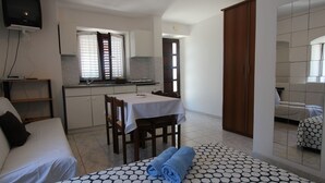 A compact hotel room with a kitchenette, a dining area, and a bed.