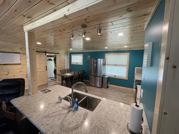 A kitchen with granite countertops, stainless steel appliances, and a dining area with a table and chairs.