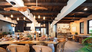 A rustic dining area with a large wooden table set for a meal, surrounded by woven chairs.