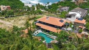 A resort with a swimming pool, multiple buildings, and a view of the ocean.