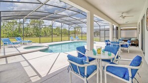 A covered outdoor area with a pool, lounge chairs, and a table with chairs.