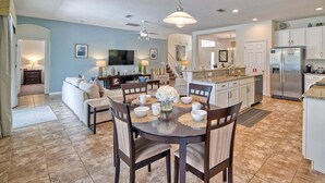 A spacious kitchen with a dining area, a TV, and a refrigerator.