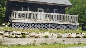 A wooden cabin with a porch, surrounded by rocks and trees.
