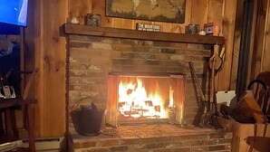 A fireplace with a sign above it, a television on the left, and a wooden wall.