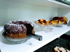 A cake on a glass stand with a knife. - Hotel Bless (Cascavel)