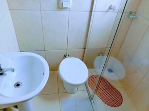 A bathroom with a sink, toilet, and glass shower enclosure. - Hotel Bless (Cascavel)