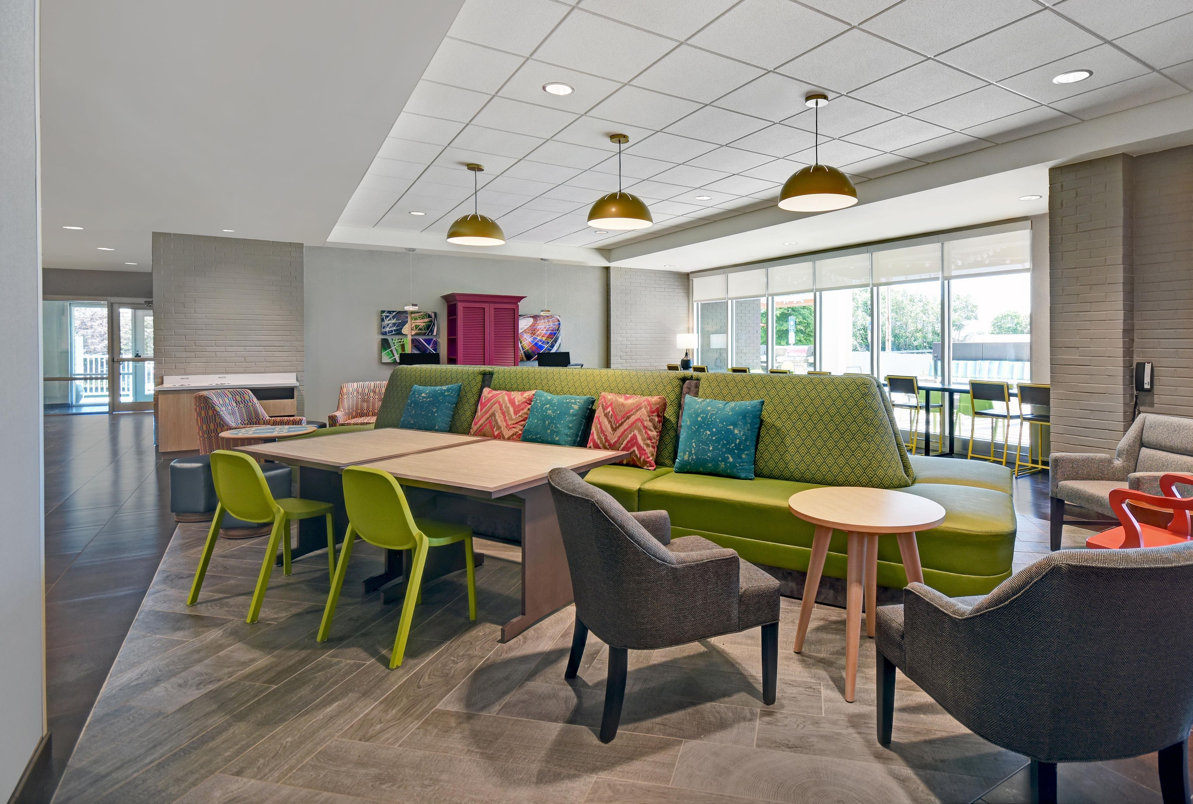 A modern lounge area with a green sofa, a wooden table, and bright green chairs.