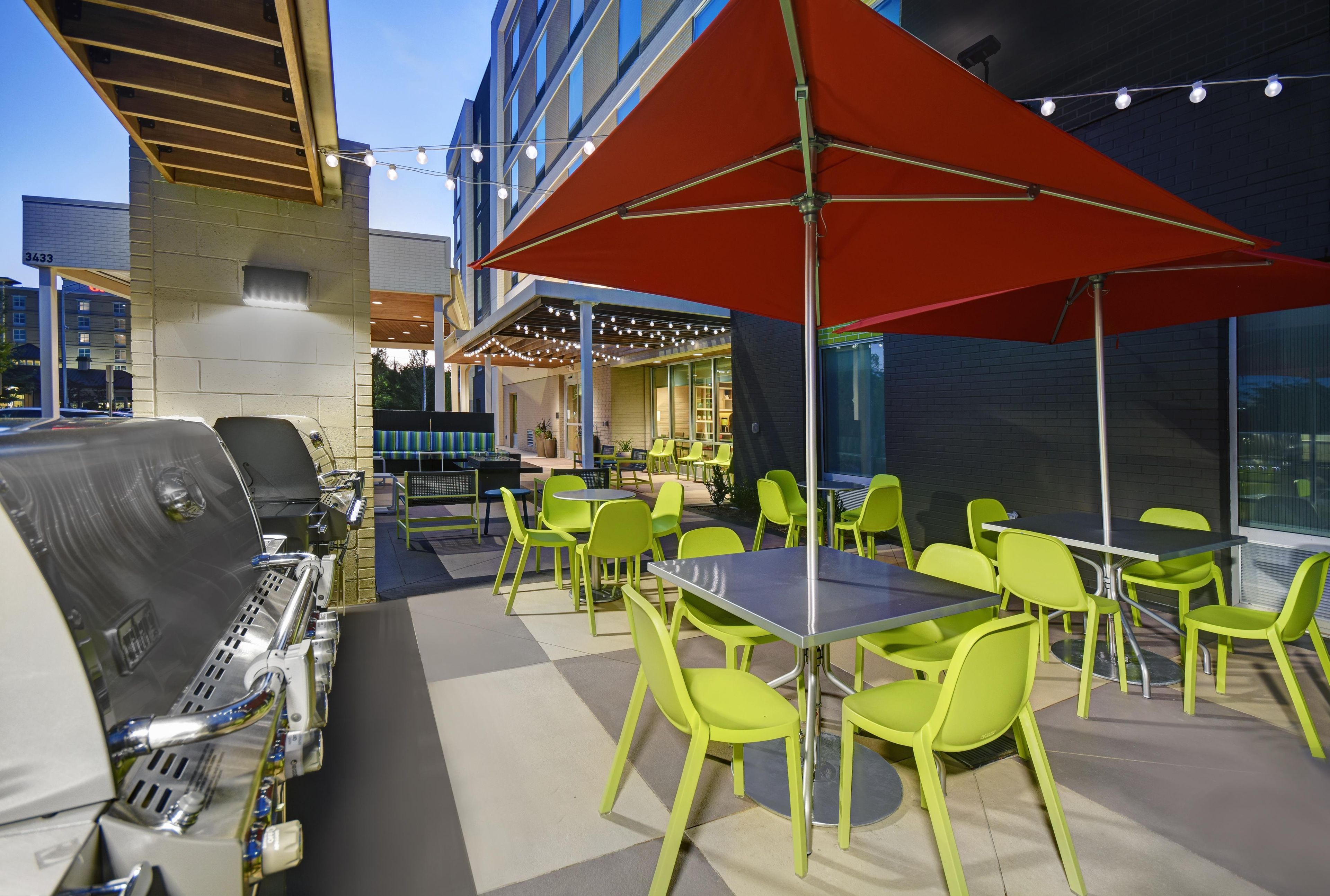 Une terrasse extérieure équipée d’un barbecue, de tables et de chaises.