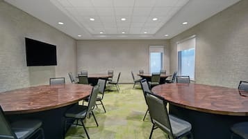 Une salle de conférence équipée d’une grande table, de chaises, d’un téléviseur à écran plat et d’une fenêtre.
