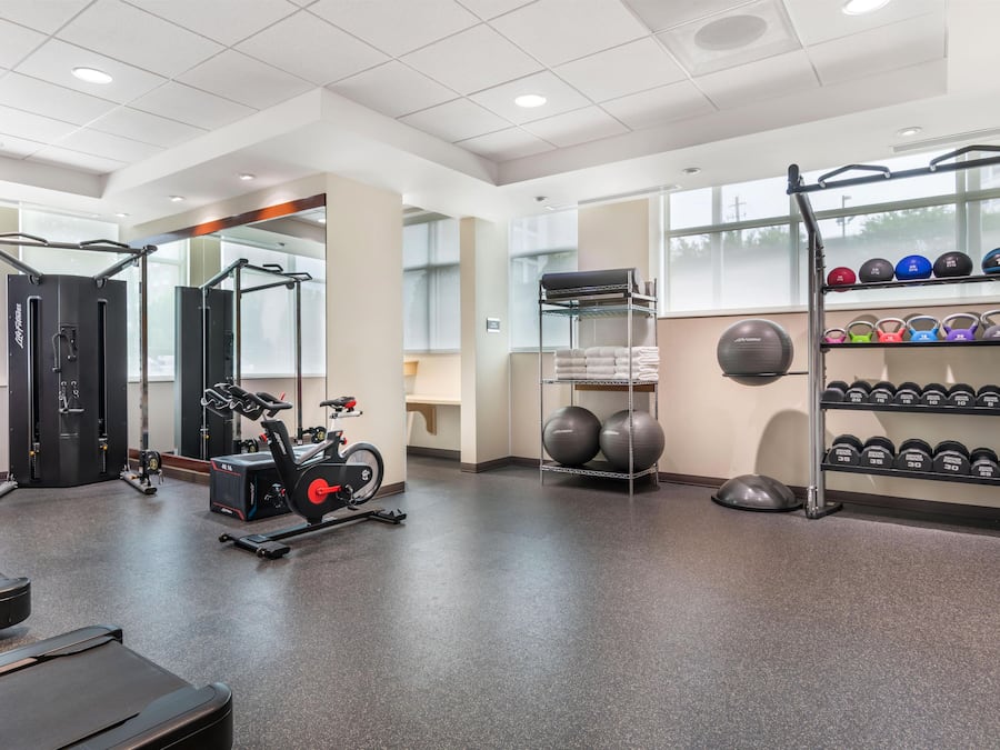 A gym with exercise equipment, including a rowing machine, a pull-up bar, and a rack of dumbbells.
