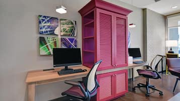 Un espacio de oficina moderno con un escritorio de madera, dos monitores negros, un archivador rojo y una silla de oficina negra.