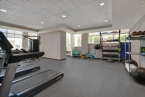 Un gimnasio con cintas de correr, equipamiento de levantamiento de pesas y pelotas de ejercicio.