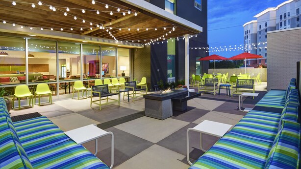 An outdoor patio area with seating, a fire pit, and string lights. - Home2 Suites by Hilton Atlanta Airport North (Atlanta)