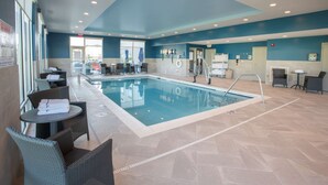A swimming pool area with lounge chairs and a table, a reception desk, and a view of the outside. - Hampton Inn by Hilton Richwood Cincinnati South (Walton)