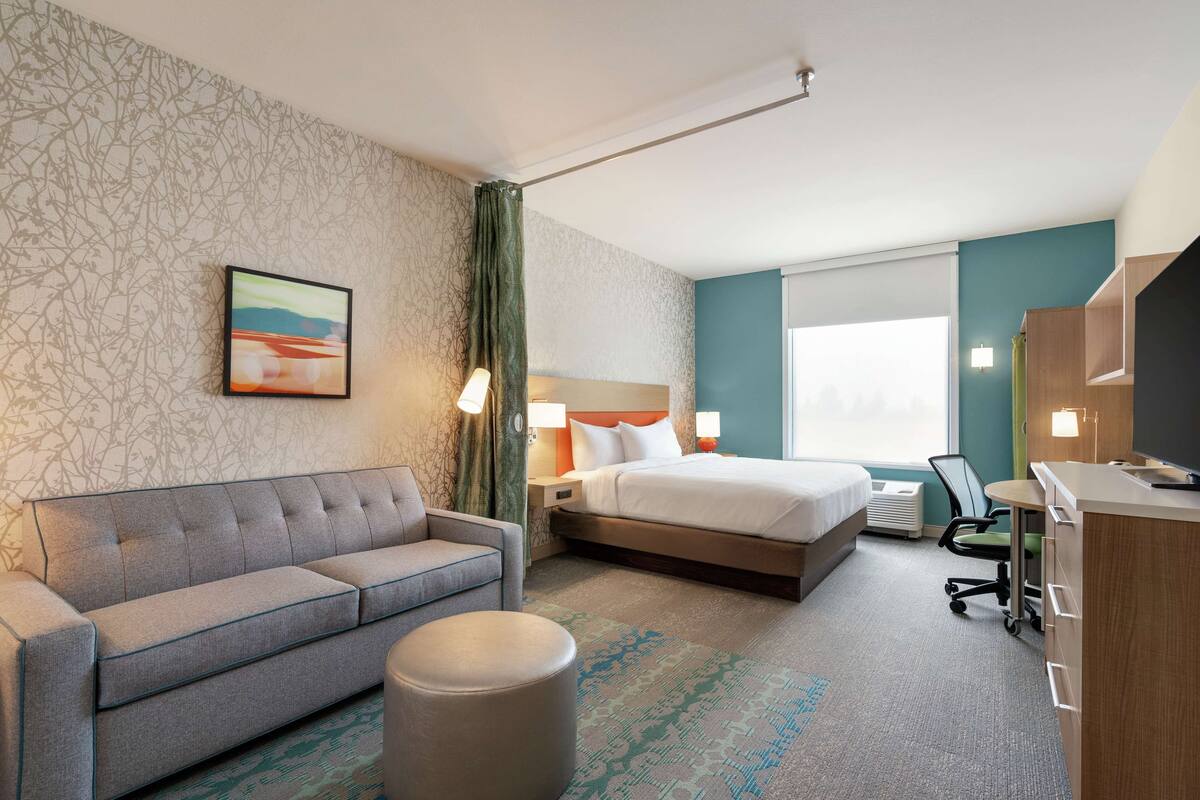 Une chambre d’hôtel avec un lit, un canapé, un bureau et une chaise.
