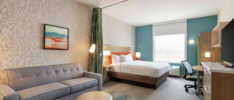 Ein Hotelzimmer mit einem Bett, einem Sofa, einem Schreibtisch und einem Stuhl.