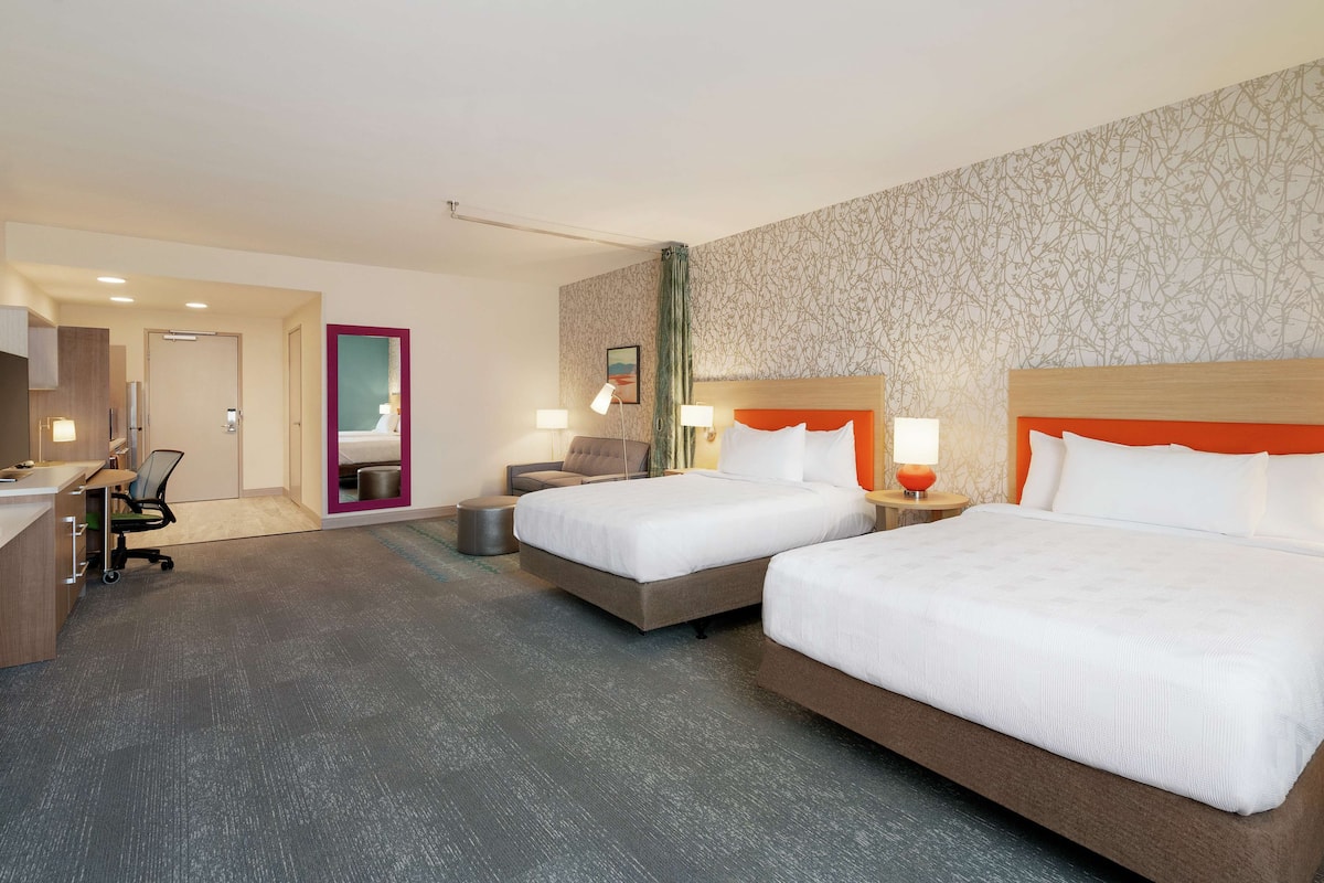 Une chambre d’hôtel avec deux lits, un bureau, une chaise et une petite table.