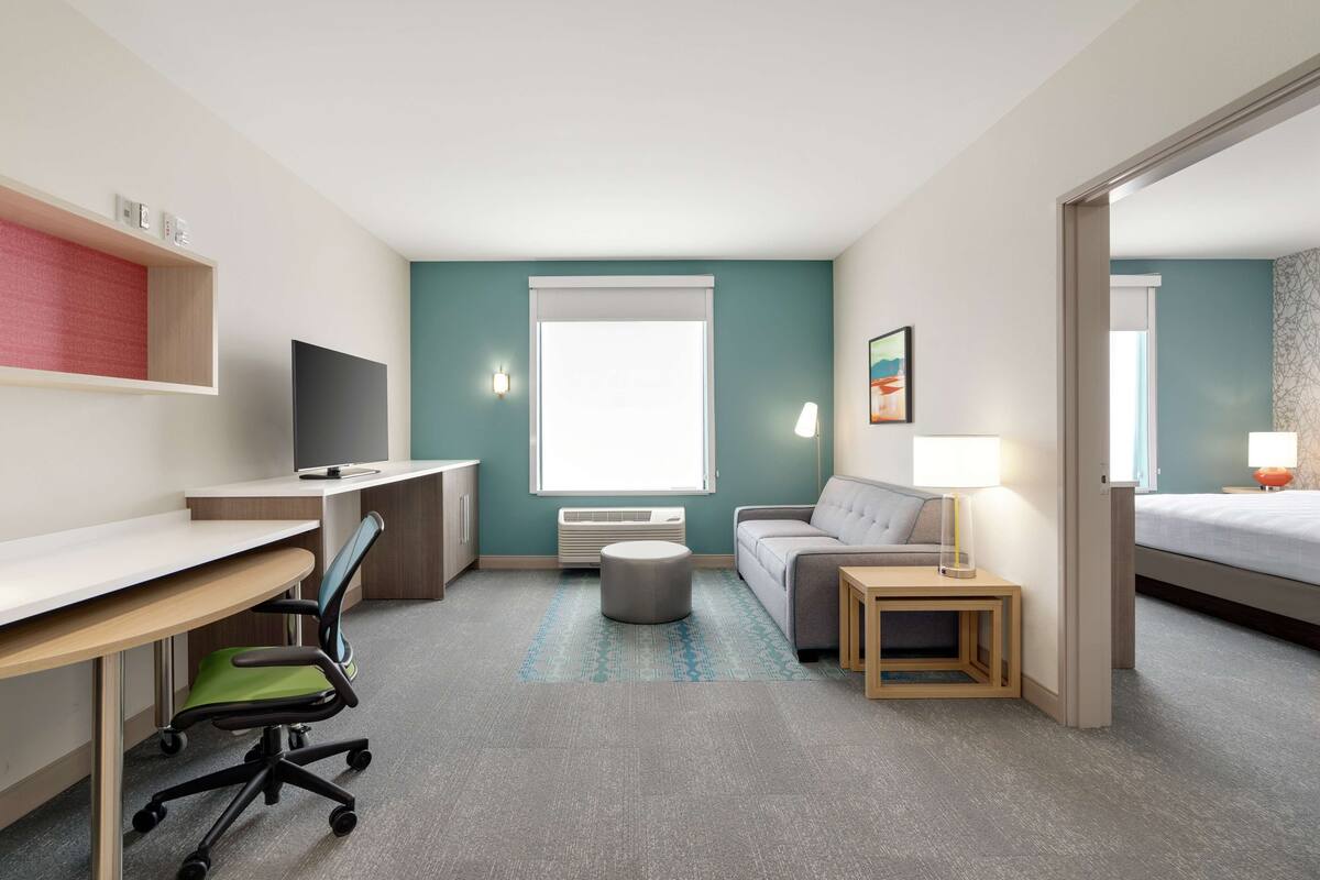 Une chambre d’hôtel moderne équipée d’un bureau, d’un fauteuil de bureau, d’un canapé et d’un lit.