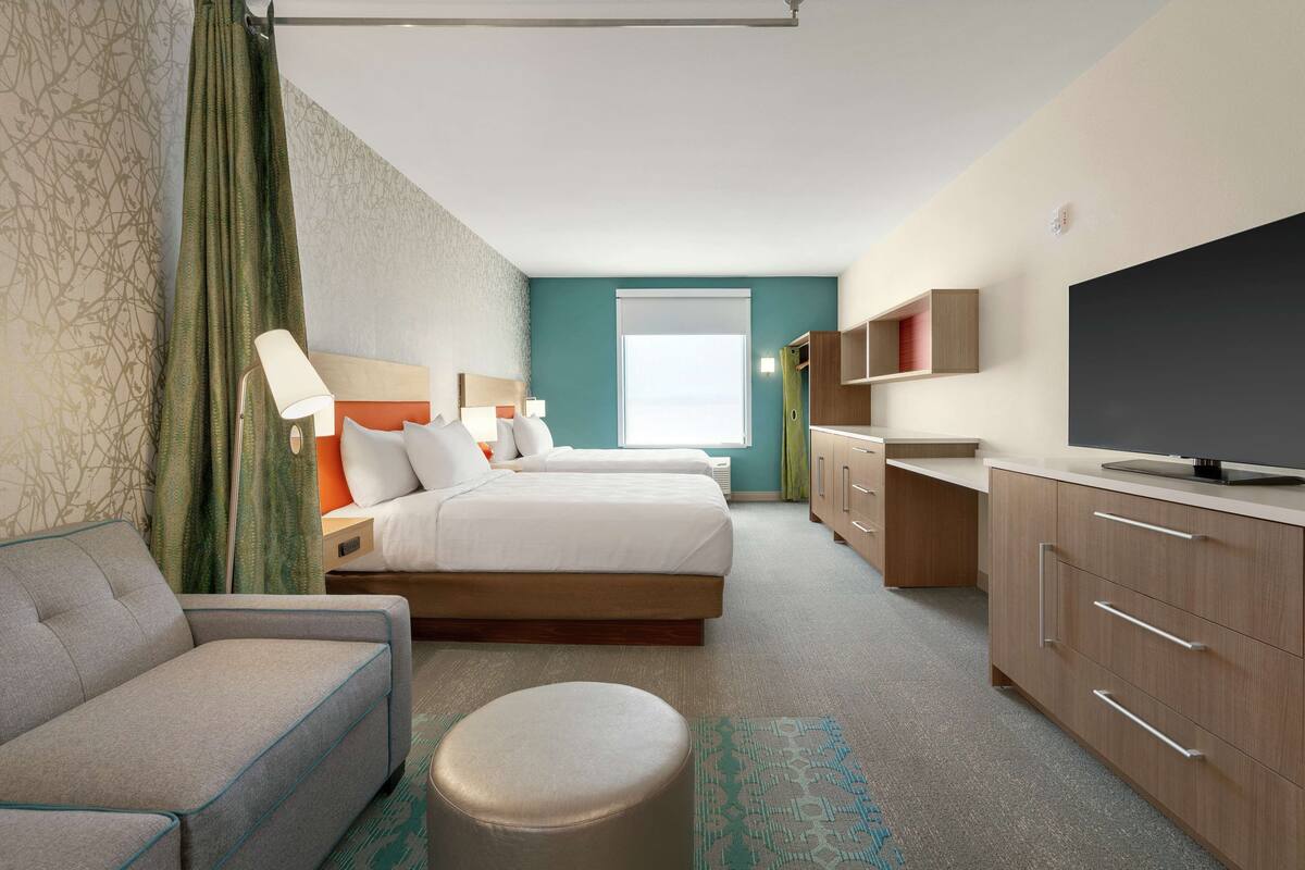 Une chambre d’hôtel avec deux lits, un canapé, une télévision et un bureau.