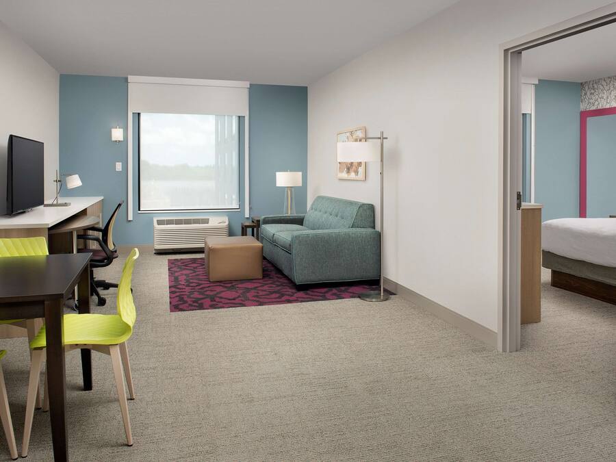 Een hotelkamer met een bureau, een groene bank, een bed en een raam met uitzicht.