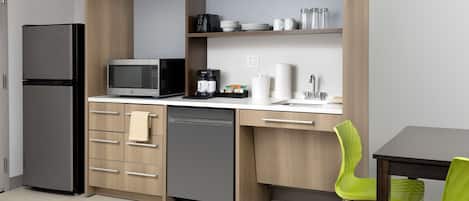 Cocina moderna con refrigerador, microondas, cafetera y pileta.