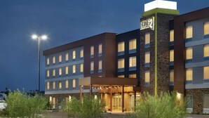 A multi-story hotel with a prominent entrance, large windows, and a well-lit facade. - Home2 Suites by Hilton Mesa Longbow, AZ (Mesa)