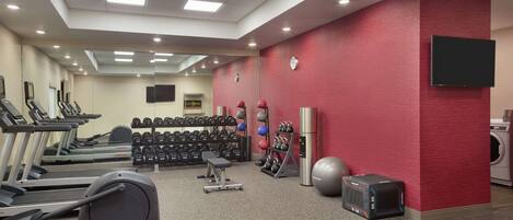 A gym with treadmills, dumbbells, kettlebells, a stationary bike, and a rowing machine.