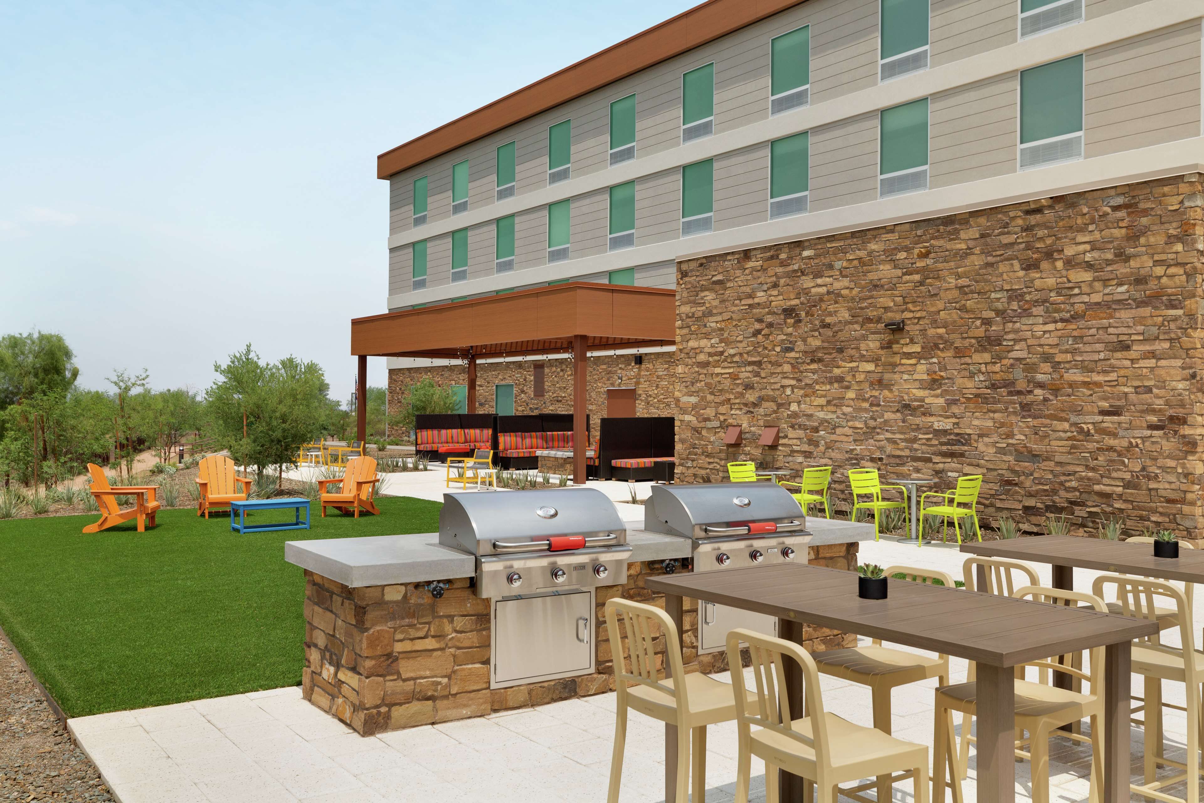 An outdoor patio with two barbecue grills, a covered seating area, and a stone wall.
