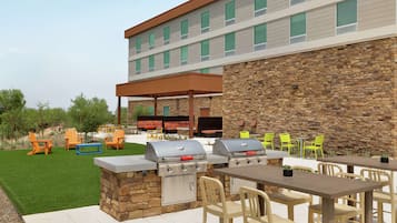 An outdoor patio with two barbecue grills, a covered seating area, and a stone wall.